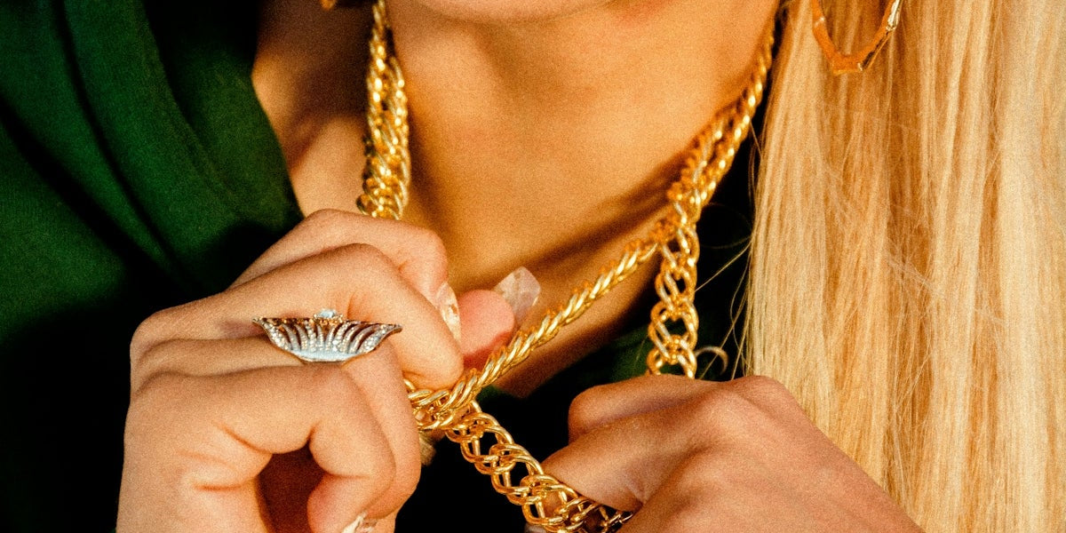 woman holding her gold-colored necklace