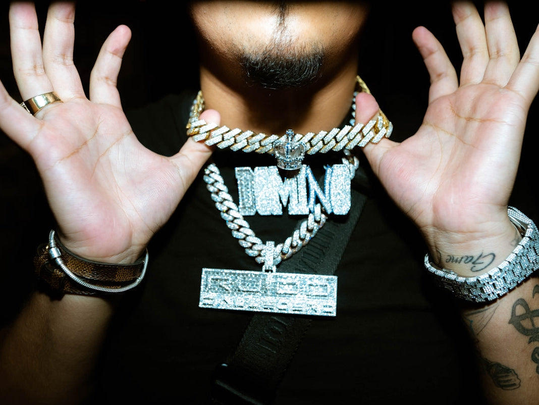 a man holding his hands up with a chain around his neck