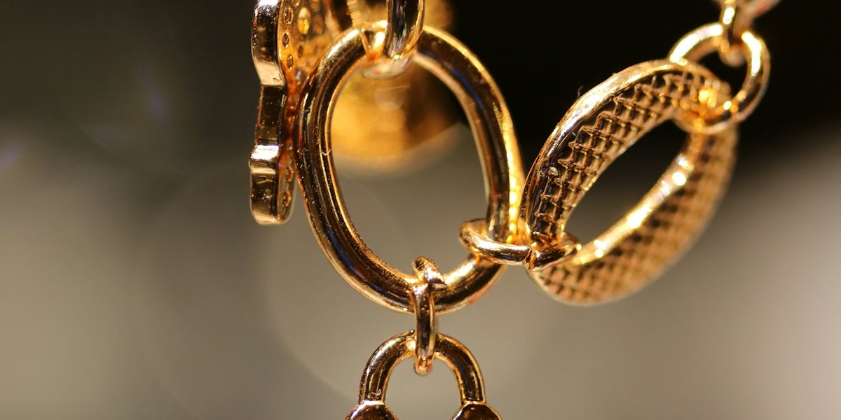 A close up of a gold necklace with a key