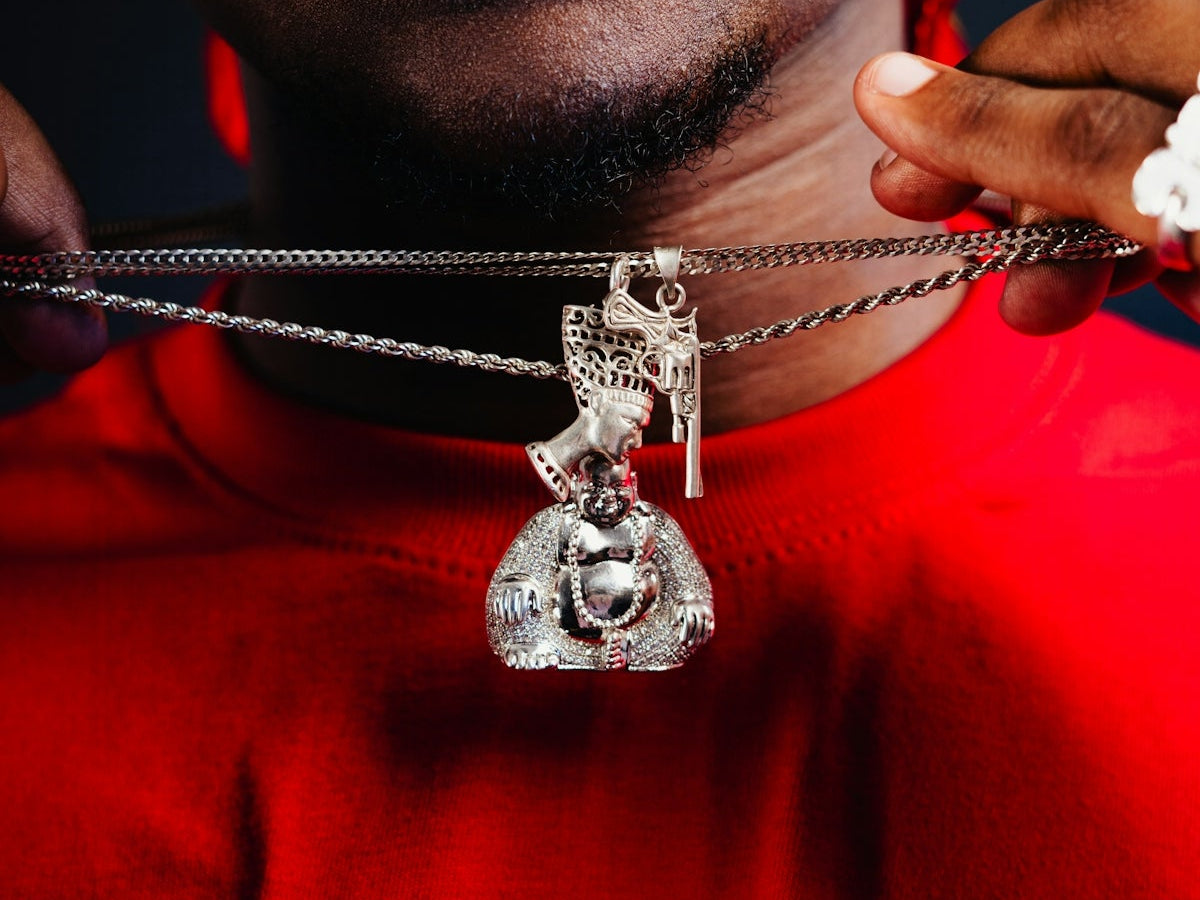 A man wearing a red shirt holding a silver necklace