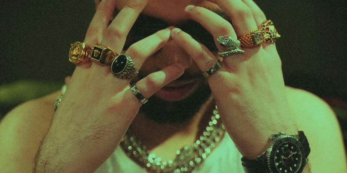 A man is wearing jewelry, resting his head.