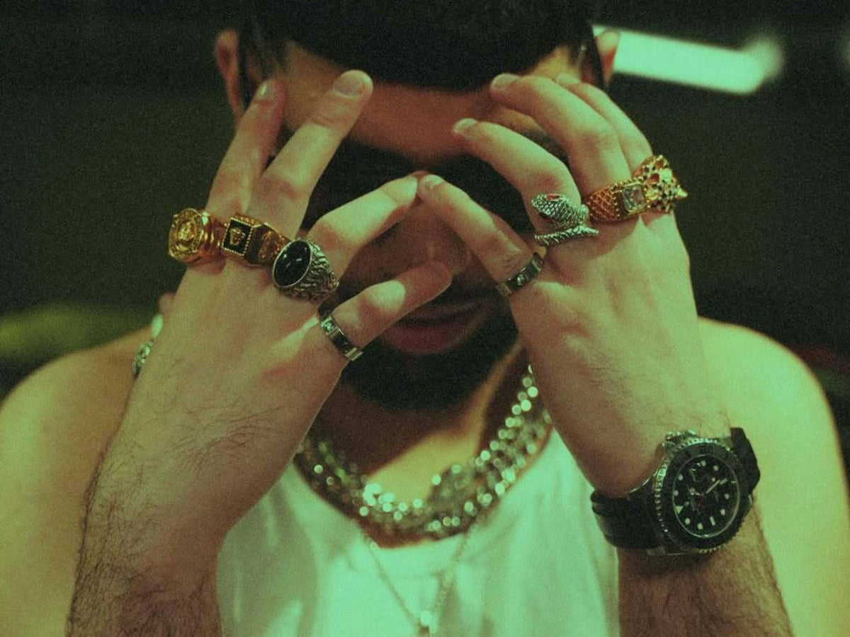 A man is wearing jewelry, resting his head.