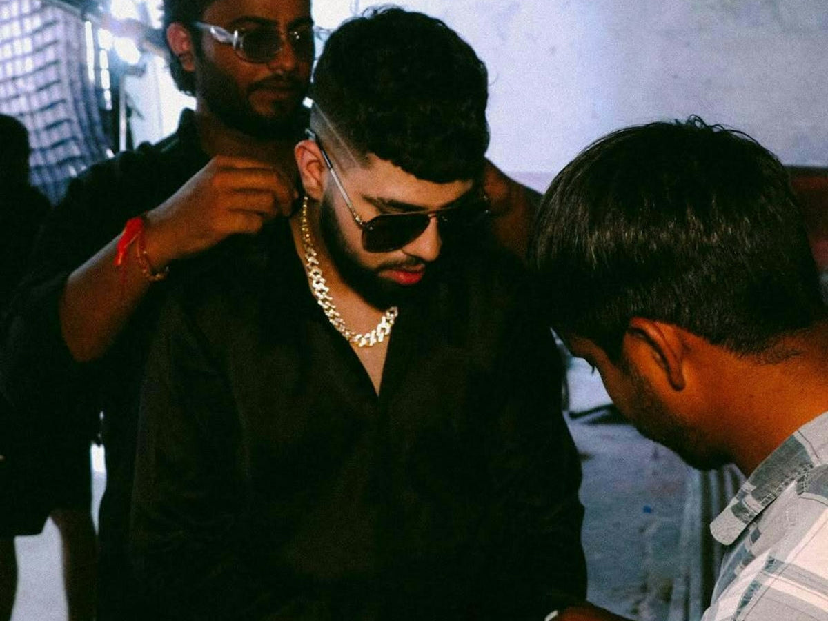 Men dressing a man in a black shirt and jewelry