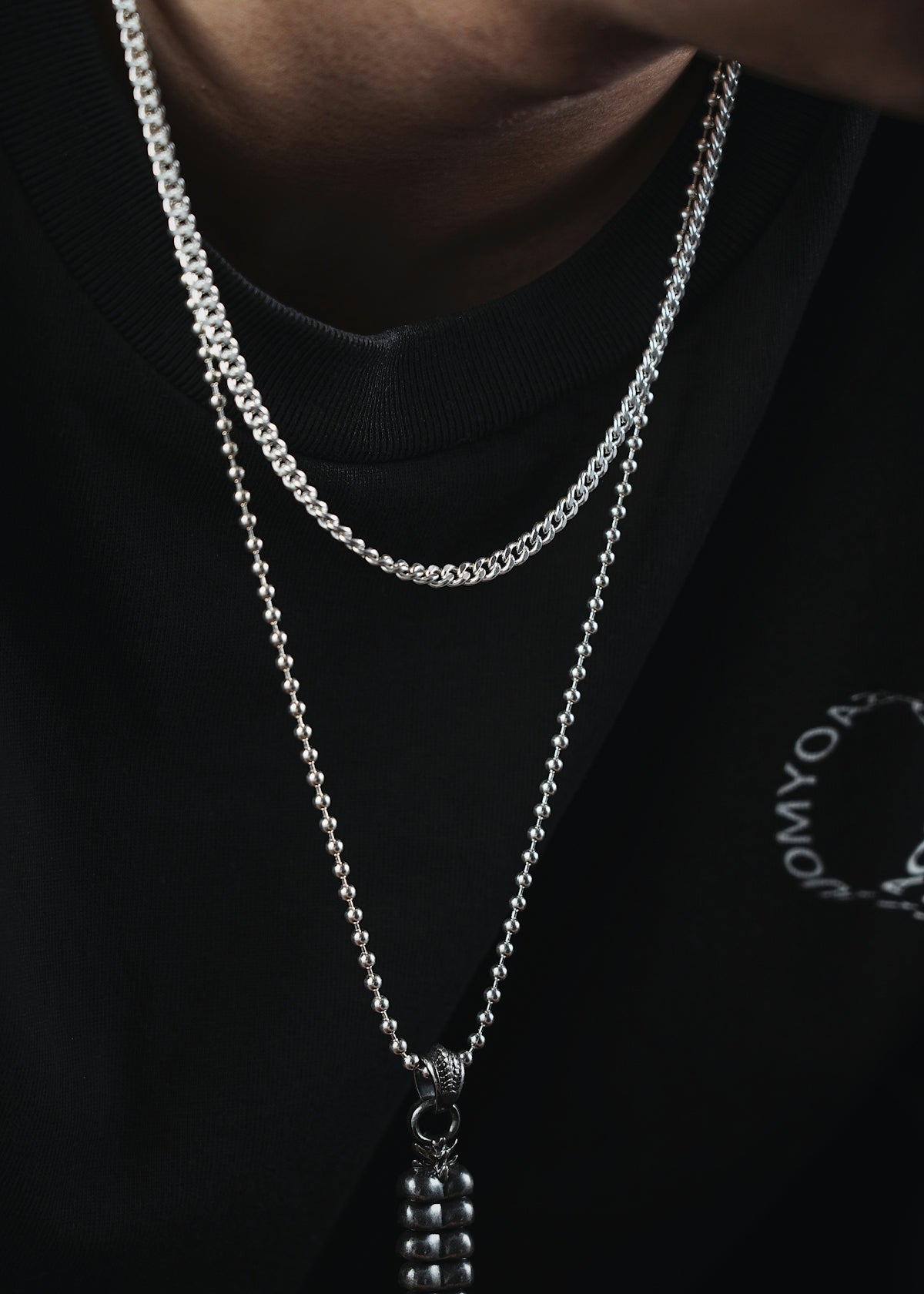 a man wearing a black shirt and a silver chain necklace