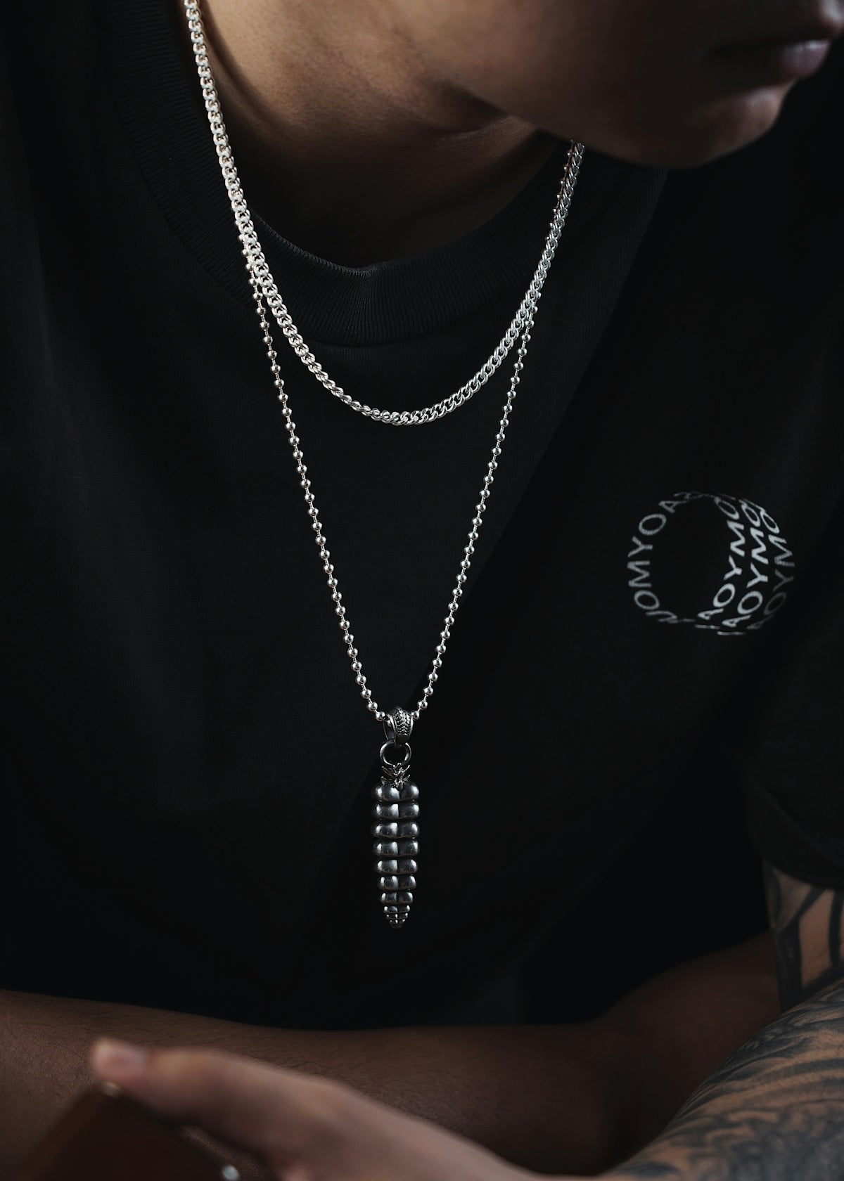 a man wearing a black shirt and a silver chain