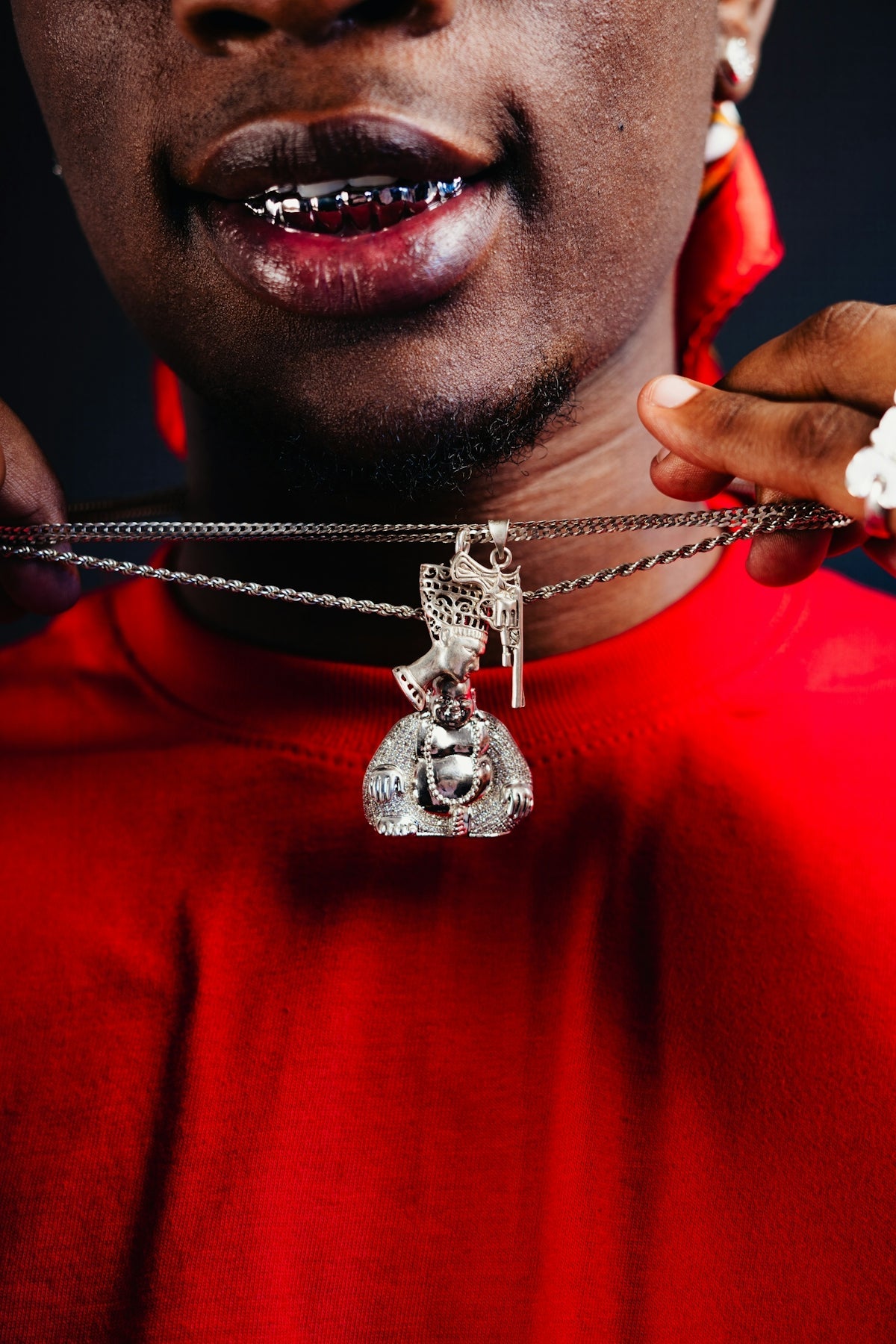 A man wearing a red shirt holding a silver necklace