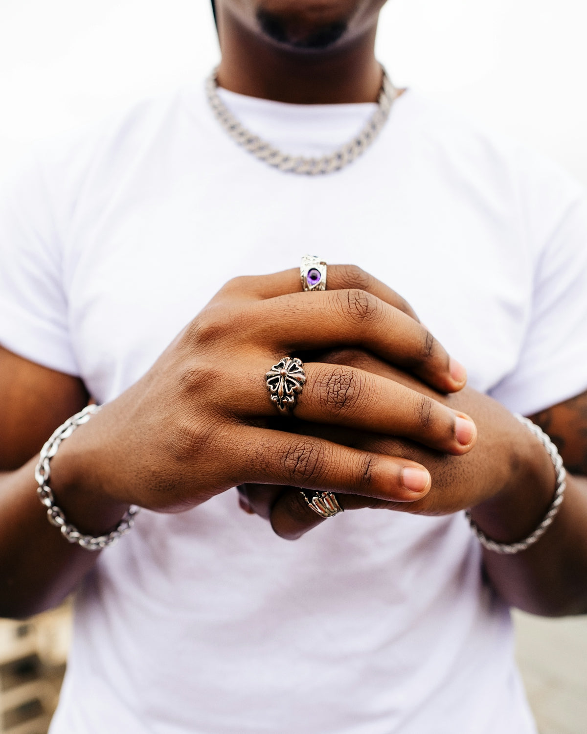 A man wearing a white t - shirt is holding his hands together