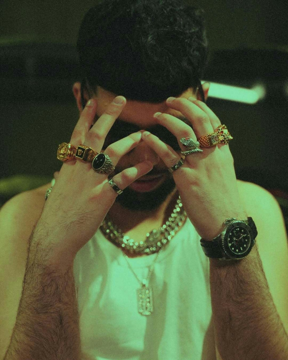 A man is wearing jewelry, resting his head.